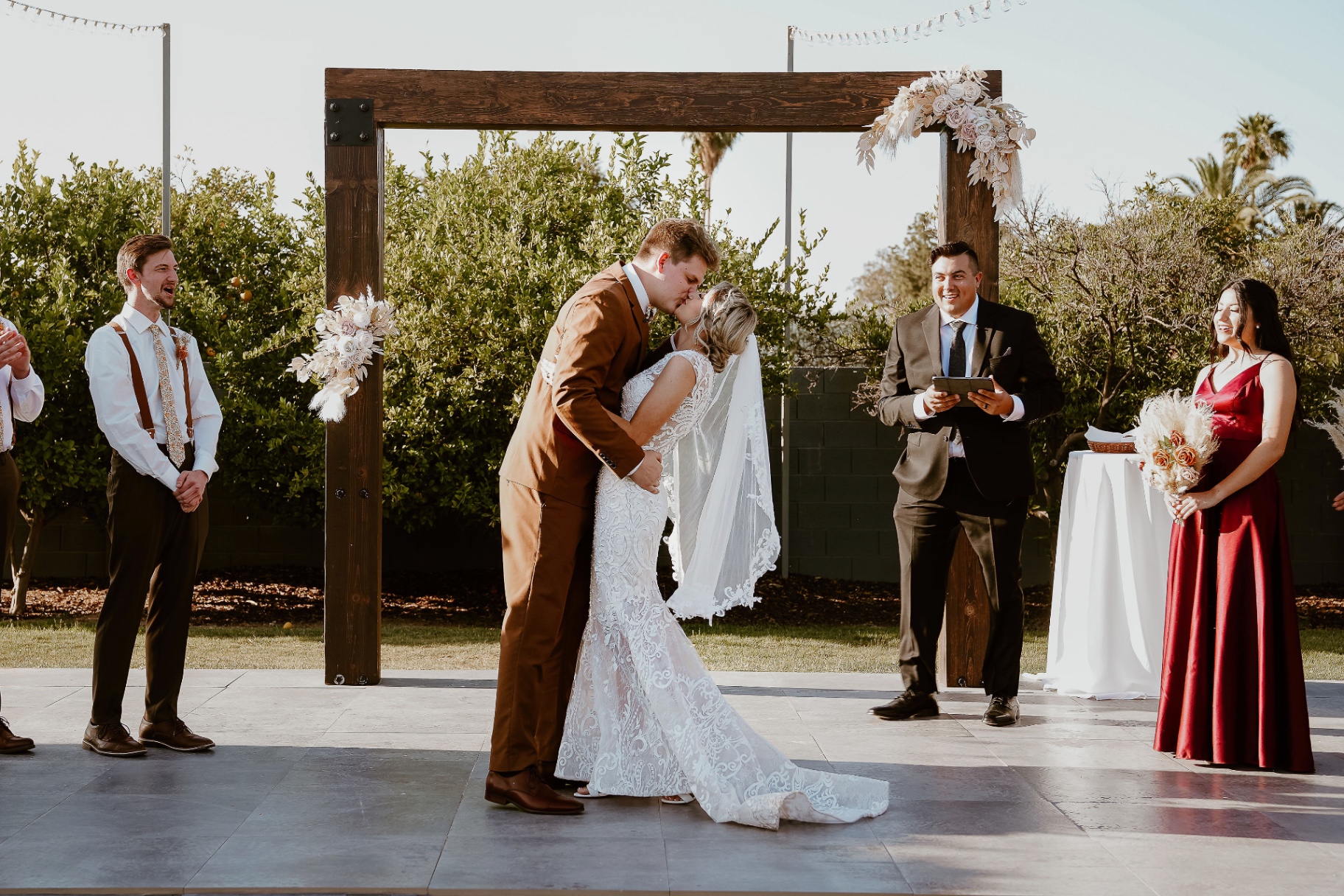 Newly married couple sharing their first kiss while Alec Russo looks on smiling