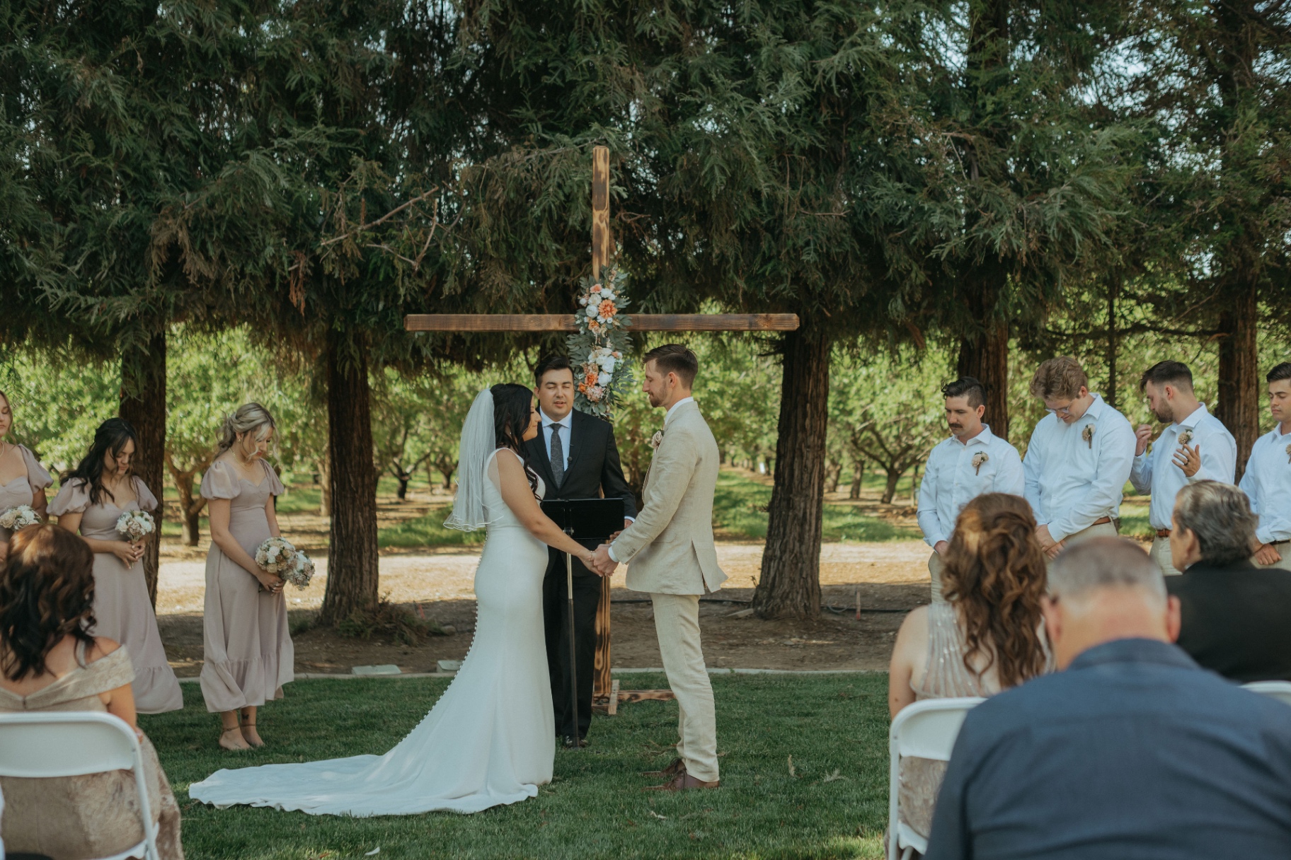 Bride and groom holding hands during an outdoor orchard ceremony as Alec Russo officiates