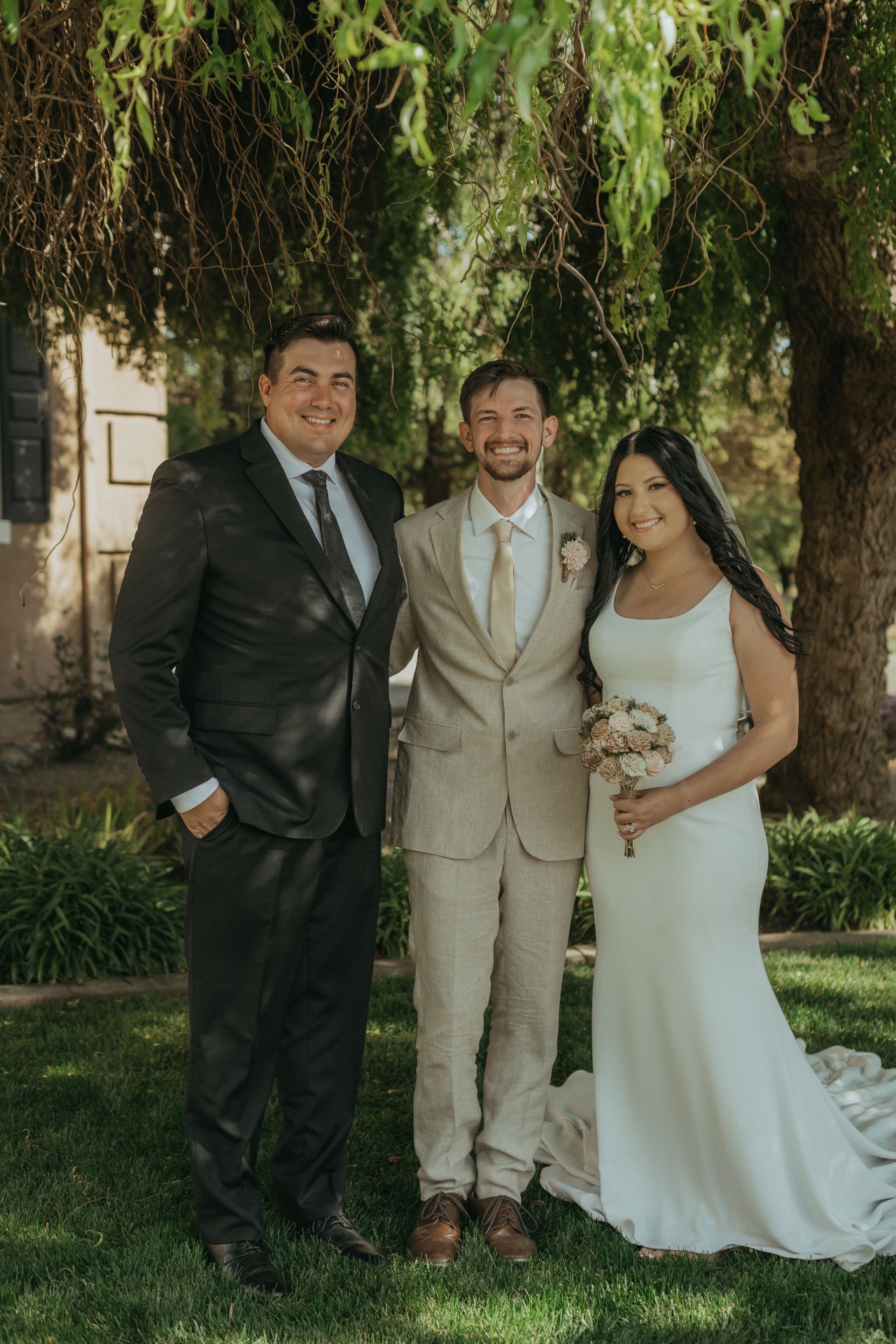 Alec Russo standing with a newly married couple beneath a willow tree