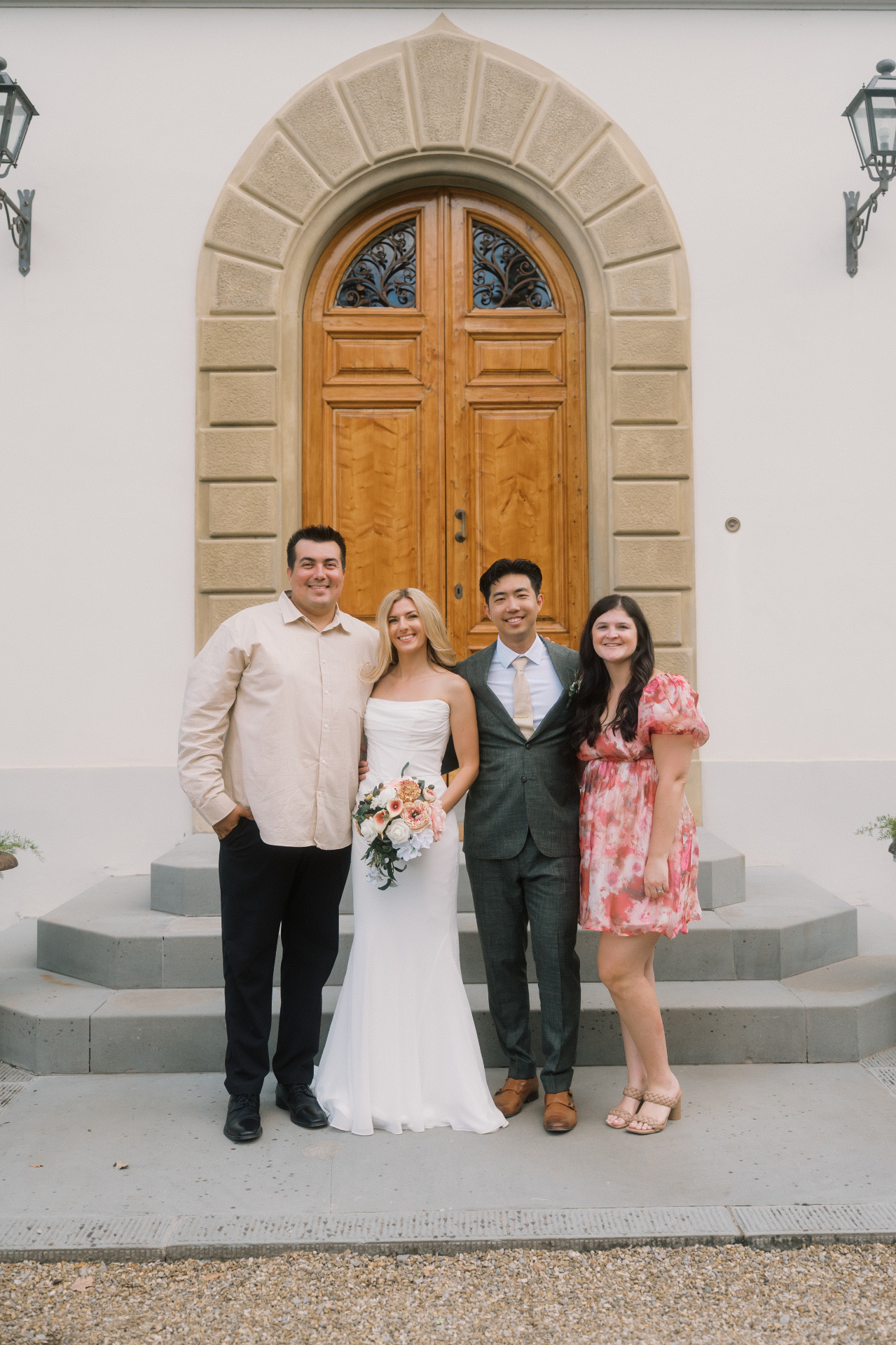 Alec Russo standing with a bride and groom in front of a carved wooden villa doorway